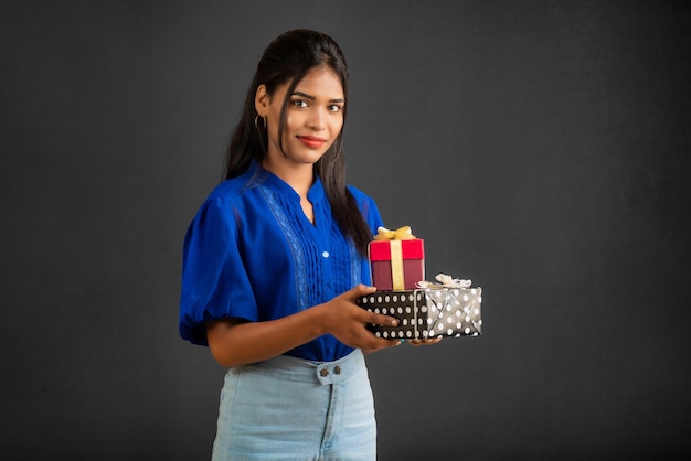 Portrait of young happy smiling Girl holding gift box on a grey background