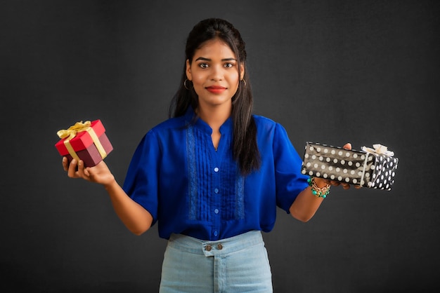 Portrait of young happy smiling Girl holding gift box on a grey background