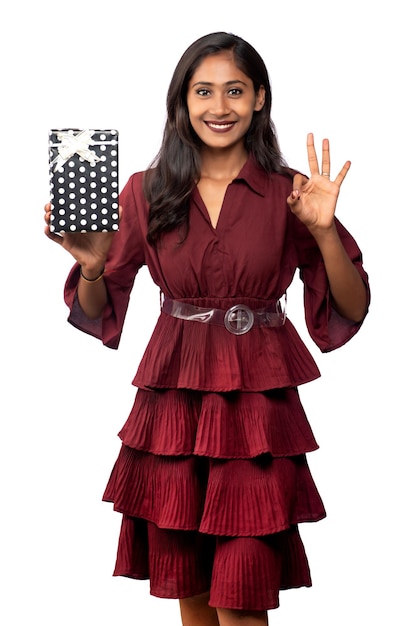 Portrait of young happy smiling Girl in red dress holding and posing with gift box on white background