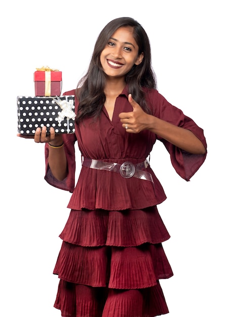 Portrait of young happy smiling Girl in red dress holding and posing with gift box on white background