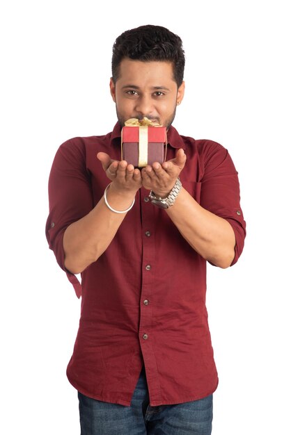 Portrait of young happy smiling handsome man holding gift box and posing on a white background