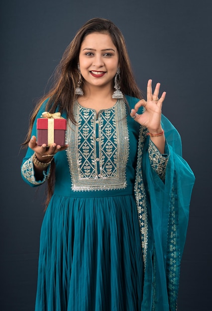 Portrait of a young happy smiling woman Girl holding gift box on a grey background