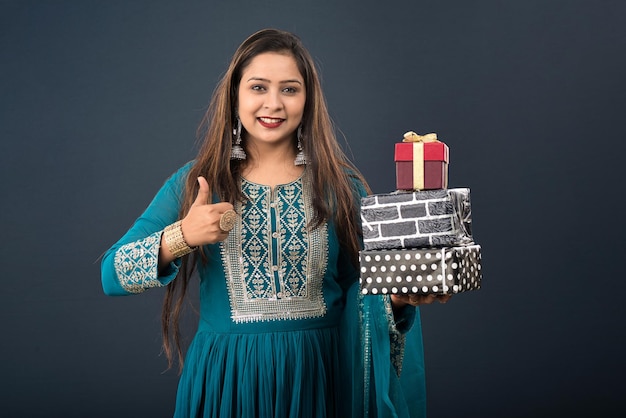 Portrait of a young happy smiling woman Girl holding gift box on a grey background