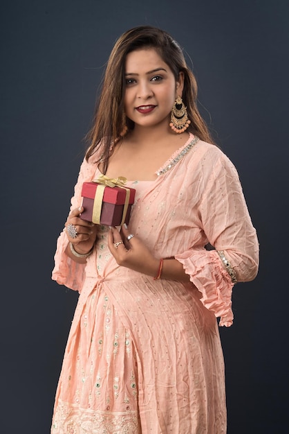 Portrait of a young happy smiling woman Girl holding gift box on a grey background