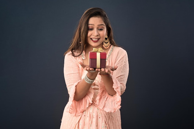 Portrait of a young happy smiling woman Girl holding gift box on a grey background