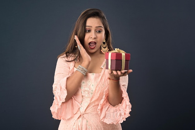 Portrait of a young happy smiling woman Girl holding gift box on a grey background