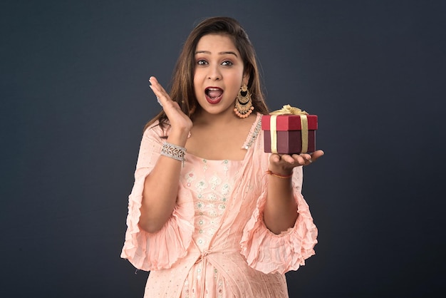 Portrait of a young happy smiling woman Girl holding gift box on a grey background