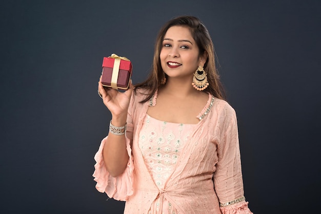 Portrait of a young happy smiling woman Girl holding gift box on a grey background