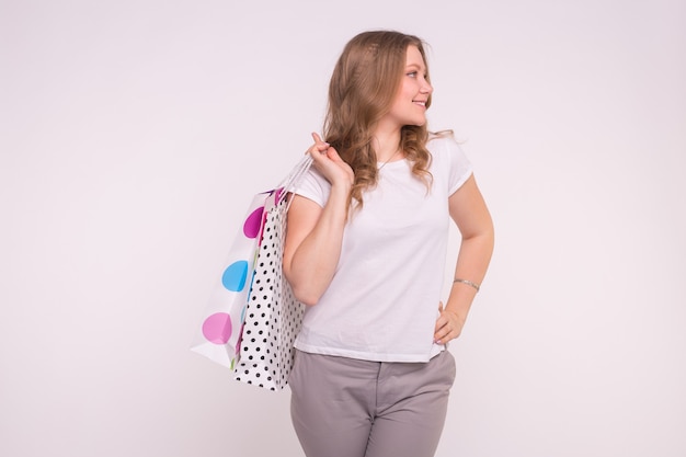 Portrait of young happy smiling woman with shopping bags on white wall