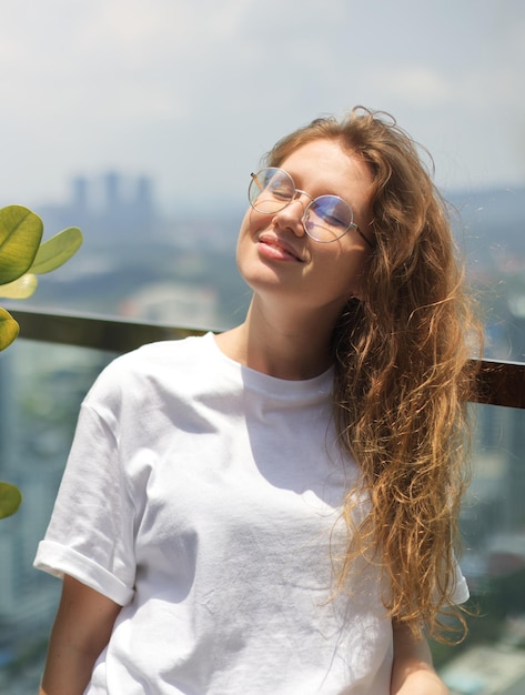 Portrait of young happy woman beautiful girl outdoors on terrace at summer sunny day enjoy day