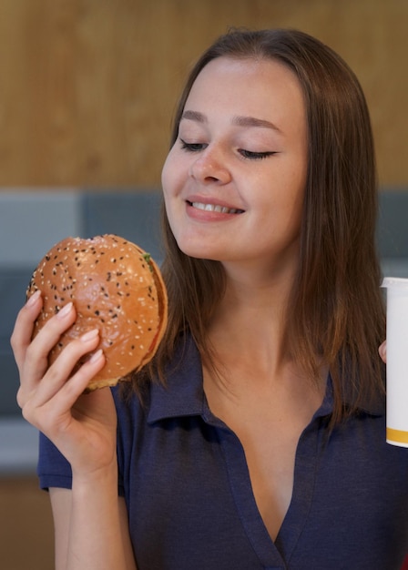 Portrait of young happy woman or beautiful teenager girl eating fast junk food tasty burger and