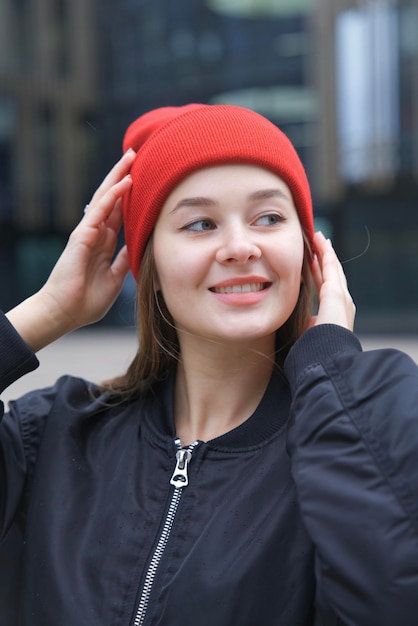 Portrait of young happy woman or teenager girl in hat looking at camera outdoors