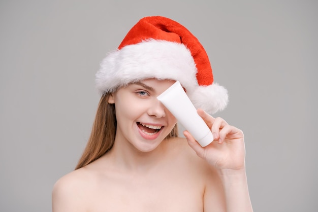 Portrait young healthy wellgroomed woman in santa hat holding white tube