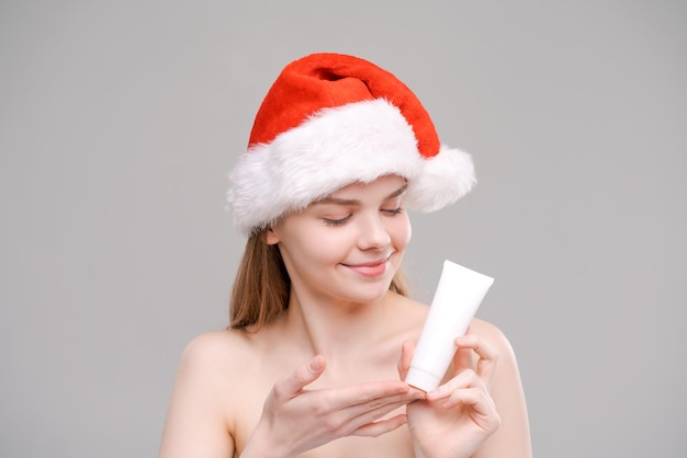 Portrait young healthy wellgroomed woman in santa hat holding white tube