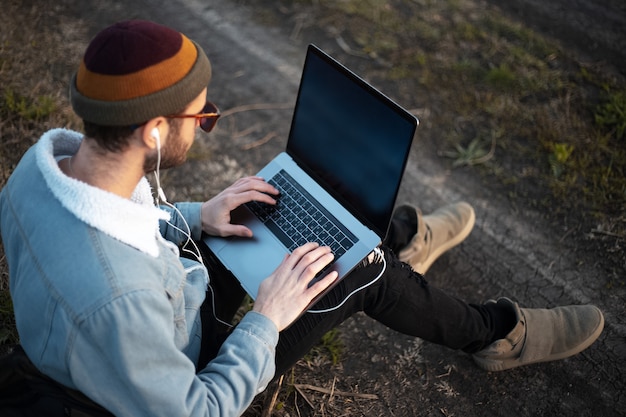 Portrait of young hipster man using laptop outdoor