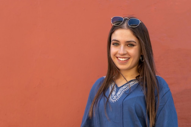 A Portrait of a young Hispanic woman smiling with space for text and with a orange background