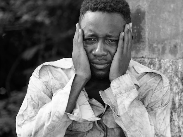 Portrait of young homeless African man on the bridge in the streets outdoors in black and white