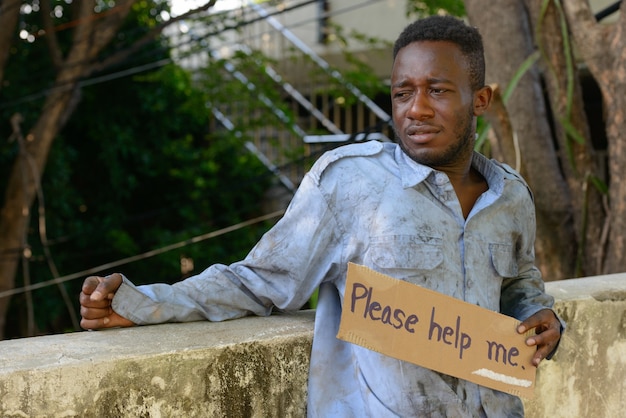 Portrait of young homeless African man on the bridge in the streets outdoors