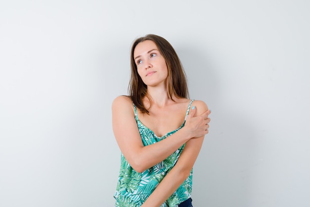 Portrait of young lady looking away with hand on her arm and looking dreamy front view