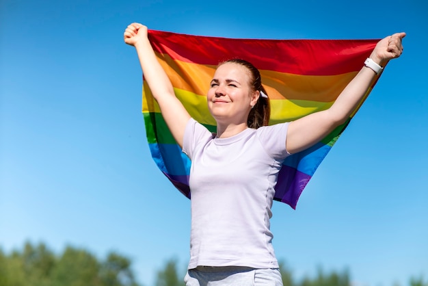 Portrait of young lesbian happy proud woman beautiful girl is waving rainbow lgbt color gay flag in