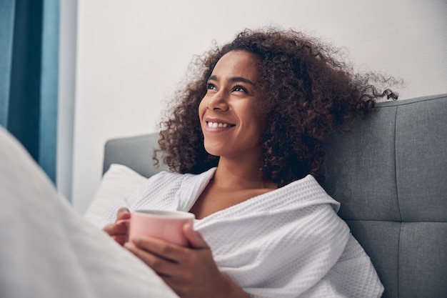 Portrait of a young lovely woman with a beaming smile reclining in bed