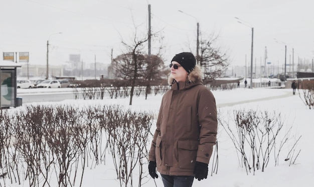 Portrait of young man in casual winter clothes with glasses on walk city