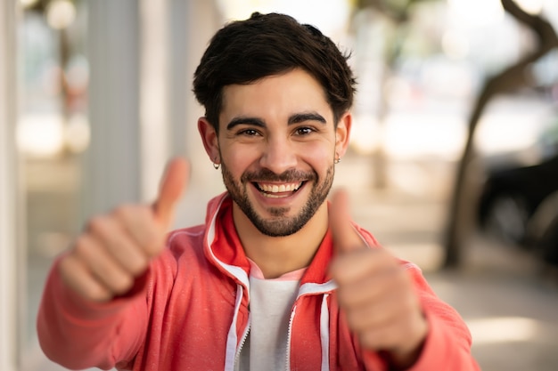 Portrait of young man celebrating victory while standing outdoors at the street. Urban and success concept.