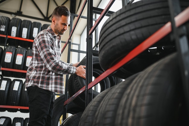 Portrait young man customer examining brand and product characteristics while buying new tires in auto department of dealership