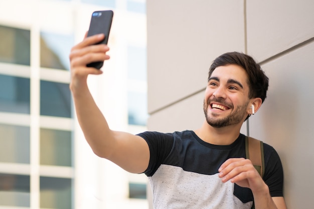 Portrait of young man having a video call on mobile phone while standing outdoors