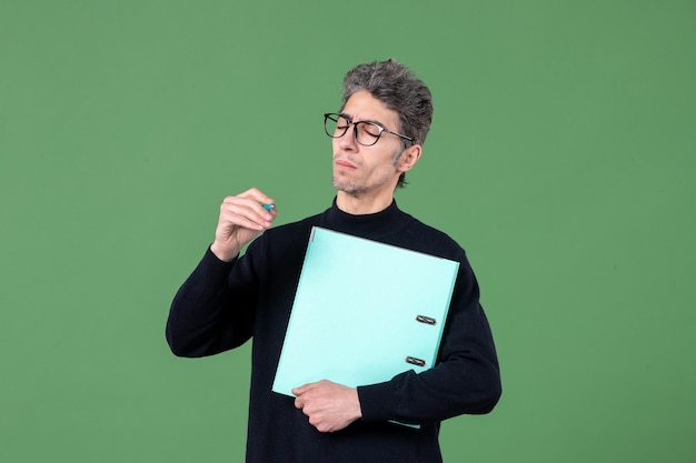 portrait of young man holding documents studio shot on green background male teacher job business