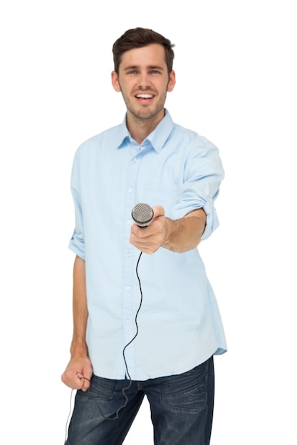 Portrait of a young man holding out microphone