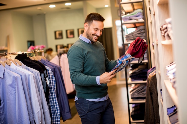 Portrait of a young man looking at clothes to buy at shop