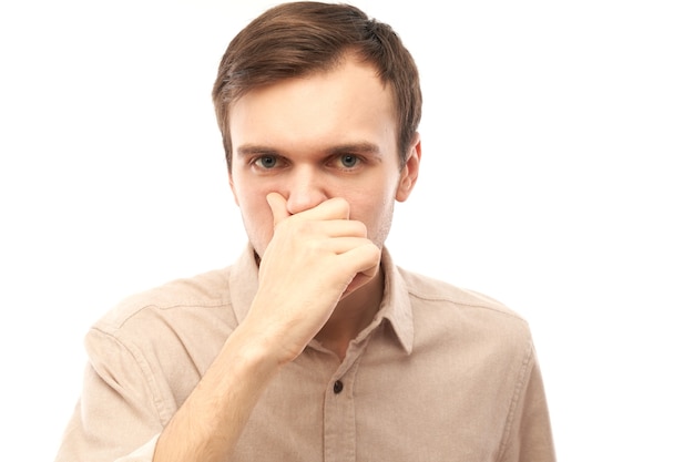 Portrait of young man pinches nose feels bad smell isolated on white studio background, halitosis, stinky sweat concept