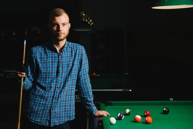 Portrait of a young man playing billiards