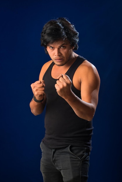 Portrait of a young man posing and showing his muscular body The concept of a healthy lifestyle on blue background