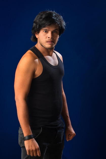 Portrait of a young man posing and showing his muscular body The concept of a healthy lifestyle on blue background