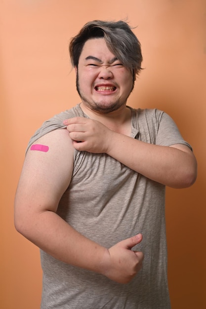 Portrait of young man showing his arm with bandage after vaccination Vaccination and immunization