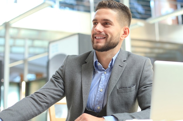 Portrait of young man sitting at his desk in the office.