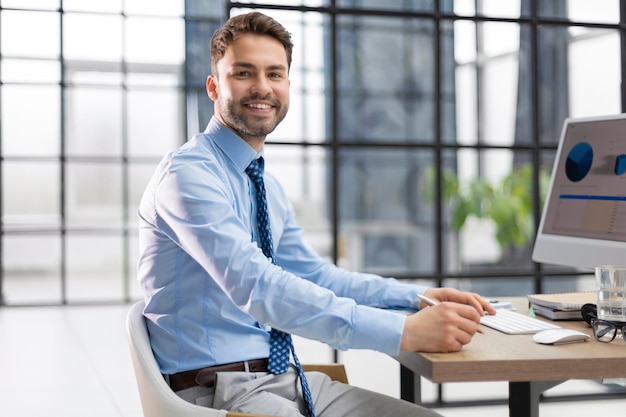 Portrait of young man sitting at his desk in the office