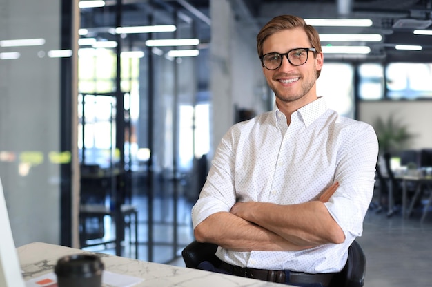 Photo portrait of young man sitting at his desk in the office