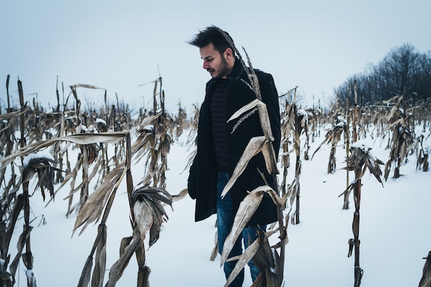 Portrait of young man standing in corn field in winter