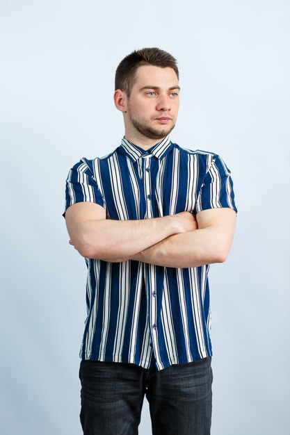 Portrait of a young man in a striped shirt over white wall