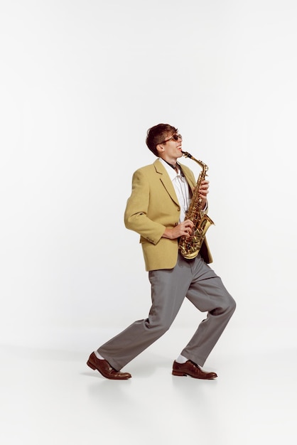 Photo portrait of young man in stylish yellow jacket playing saxophone isolated over white background jazz