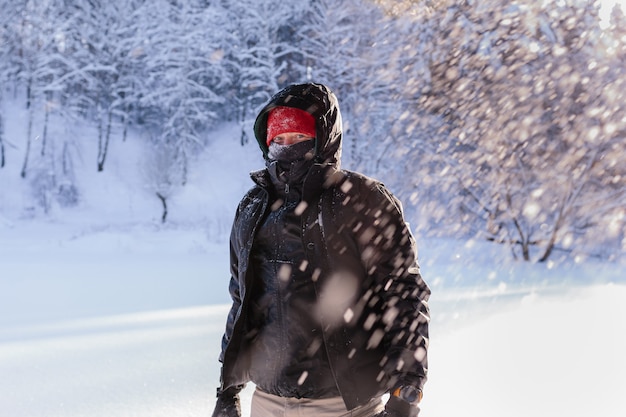 Portrait of a young man on a sunny winter day against the background of a snow-covered forest