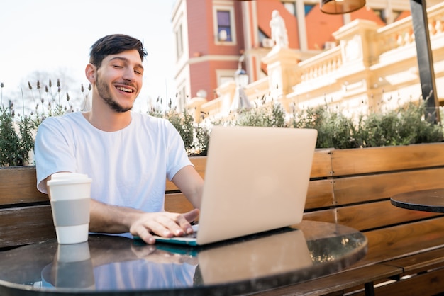 Portrait of young man using his laptop while sitting in a coffee shop. Technology and lifestyle concept.