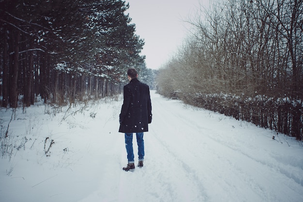 Portrait of young man walking in forest during snow storm