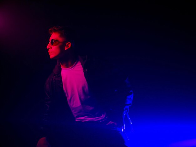 Photo portrait of young man wearing sunglasses while standing against black background