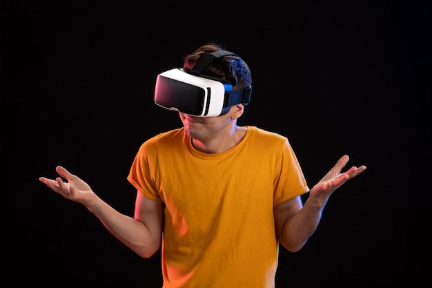 Portrait of young man wearing vr headset on dark wall