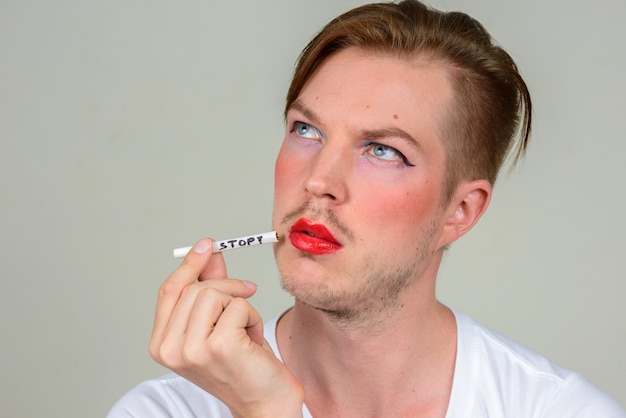 Portrait of young man with beard stubble wearing makeup