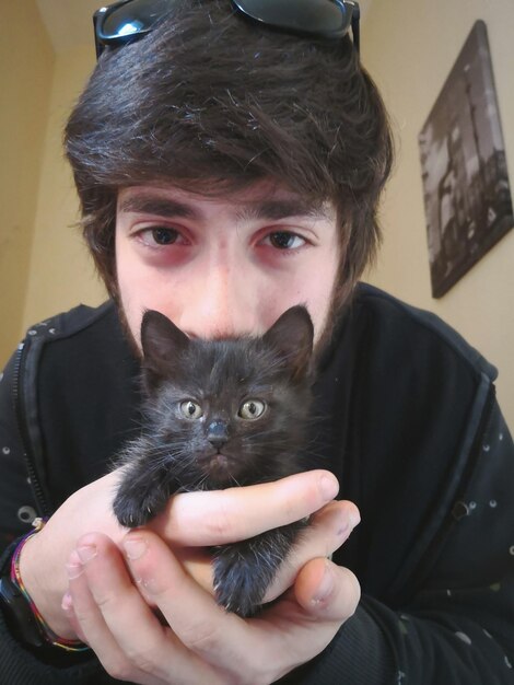 Photo portrait of young man with black kitten at home